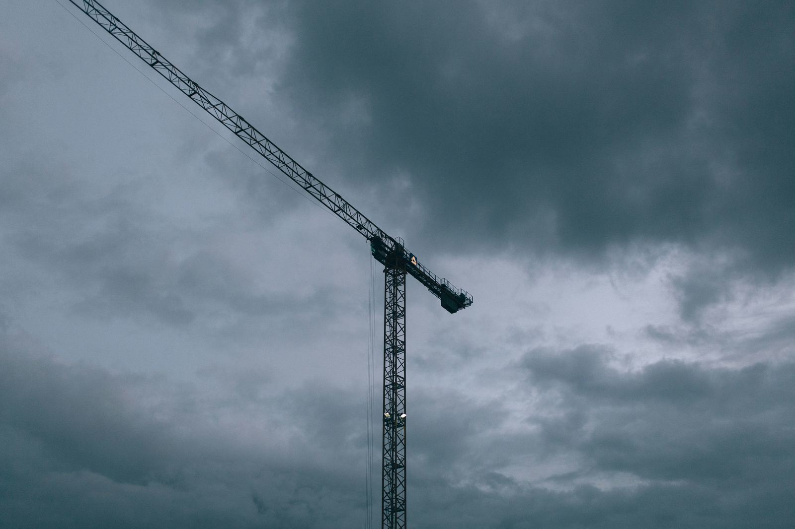 Tall construction crane against a heavy cloudy sky